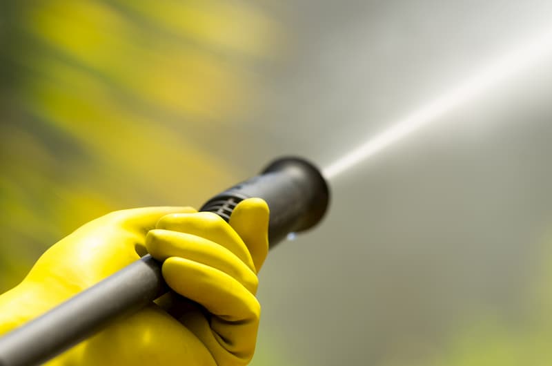 Person using a pressure washer with yellow gloves
