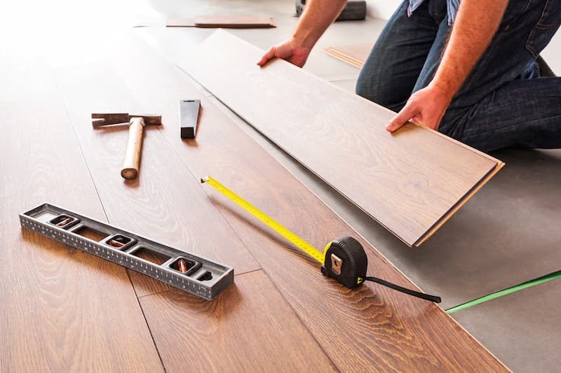 A person installing wooden flooring with tools nearby